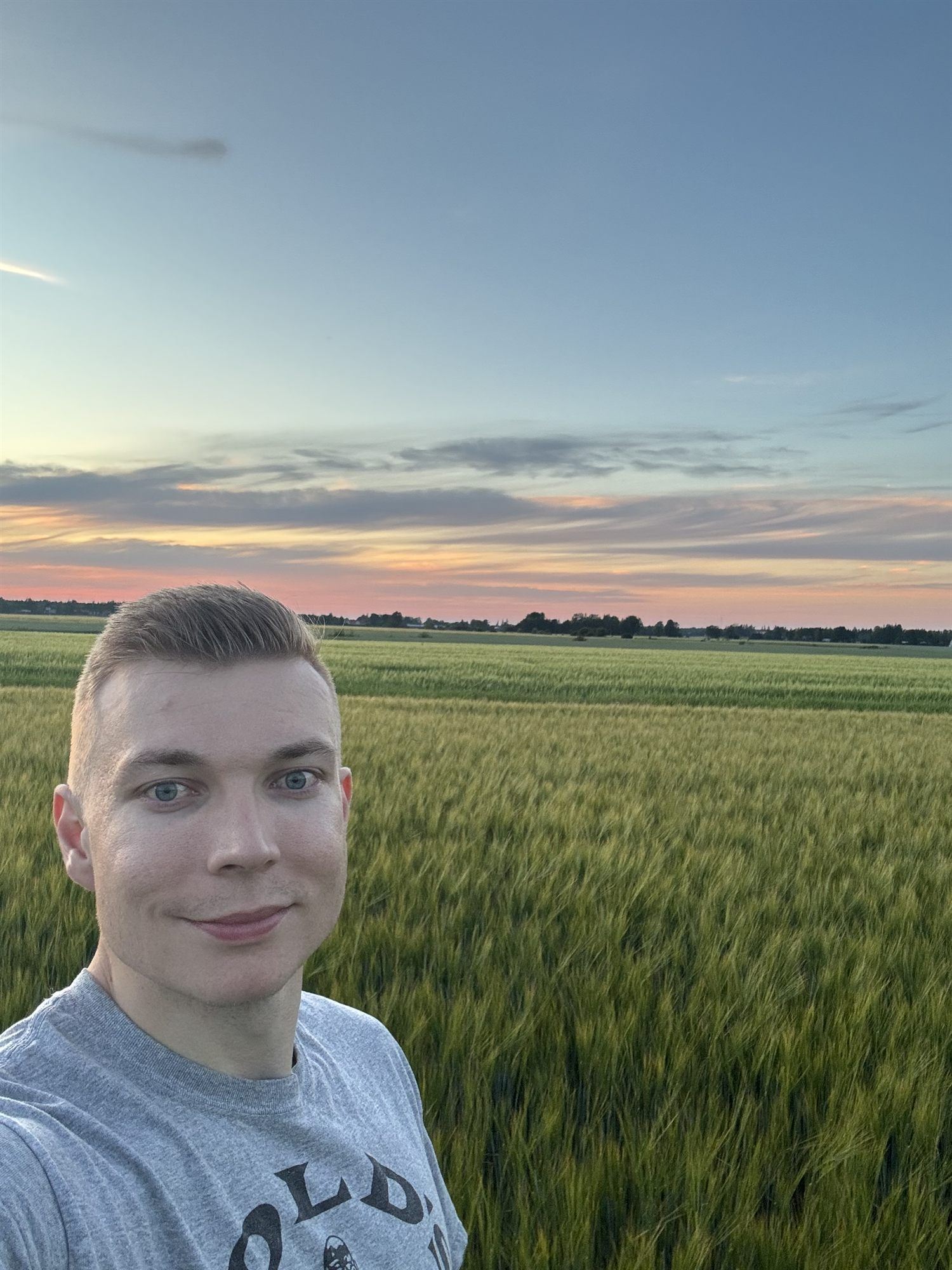 Antti Tuomela viljapellolla kesäillan auringonlaskussa
