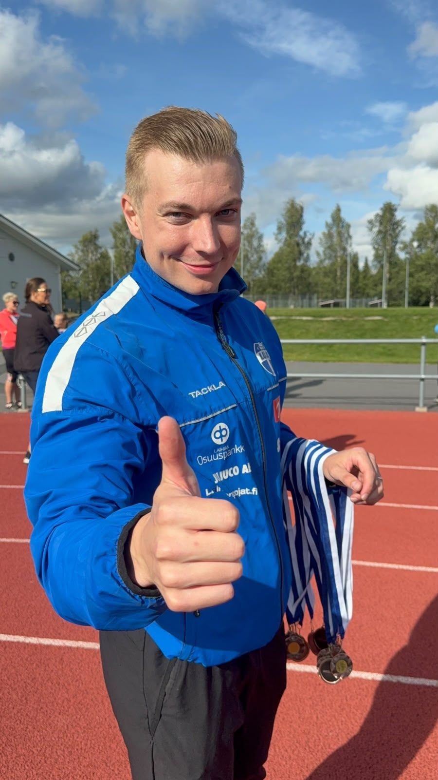 Antti Tuomela urheilukentällä mitalit kädessä